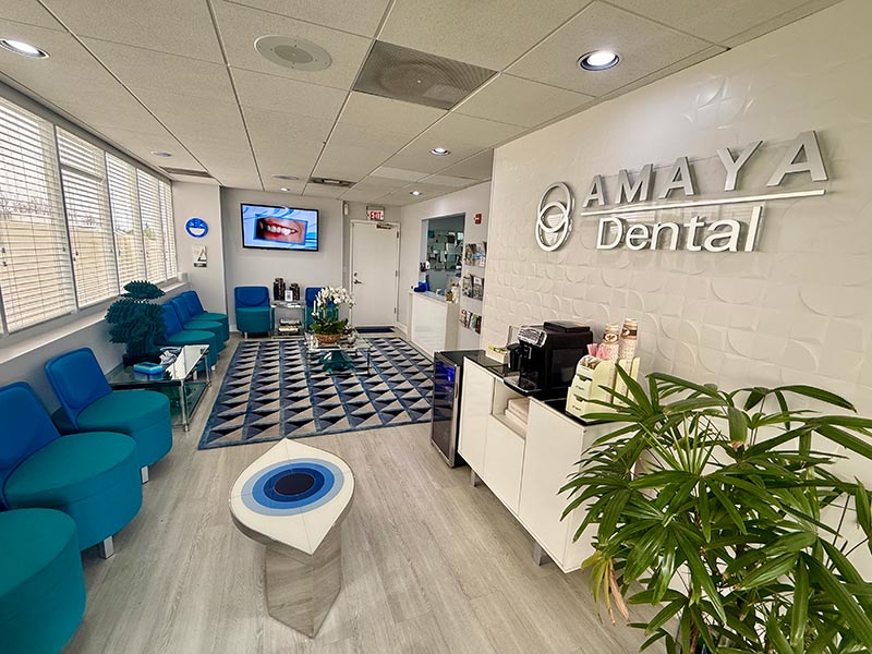 This image shows an interior space with modern furnishings, including a reception area with a sign for  AMAYA DENTAL  on the wall, indicating that this is likely a dental clinic s waiting room.